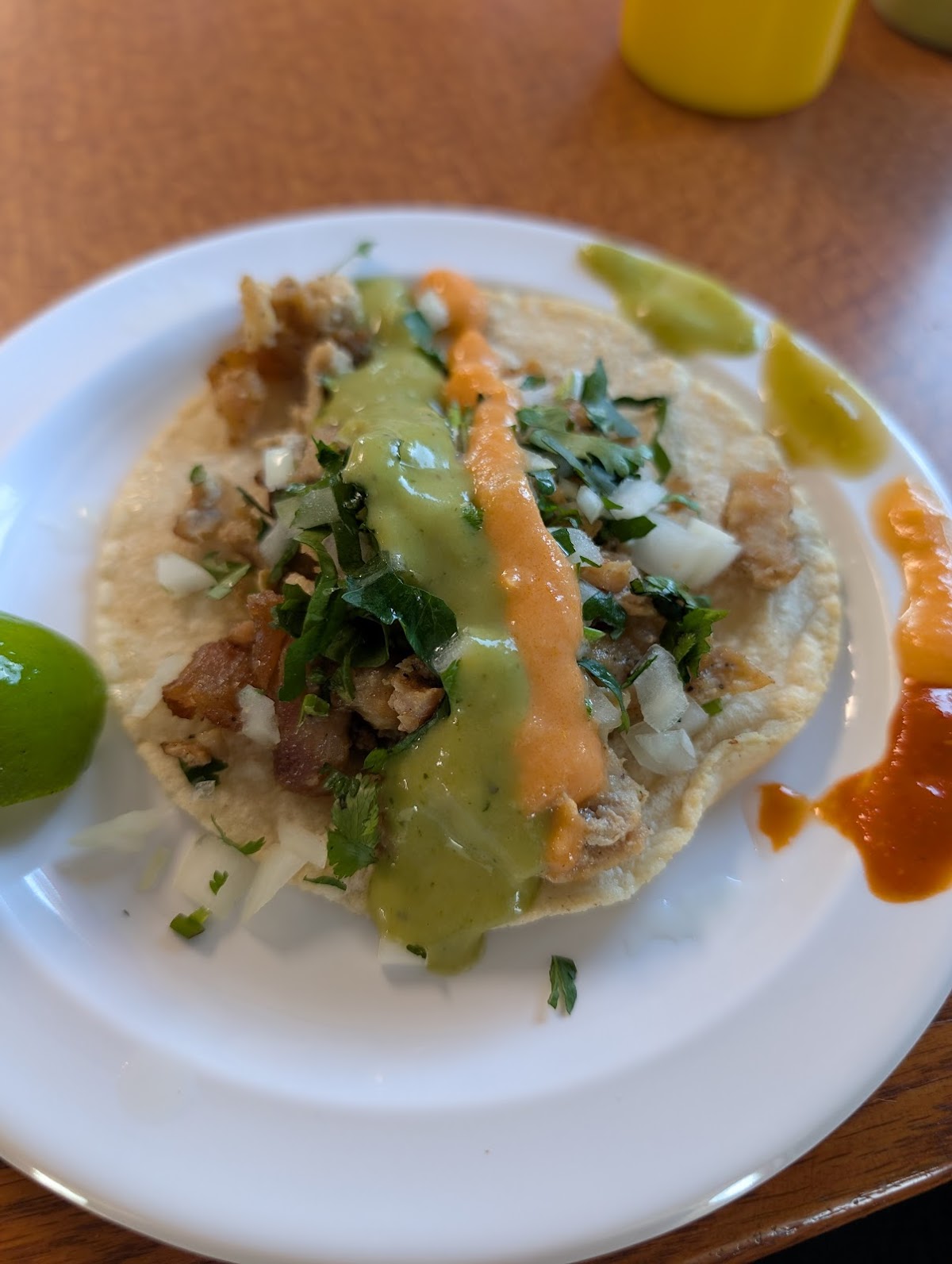 A single taco topped with green and chipotle salsa