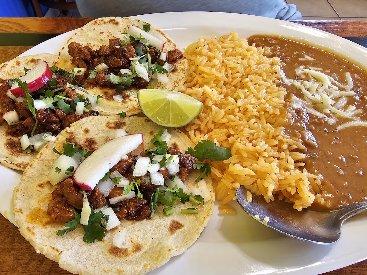 A plate of tacos al pastor with rice and beans