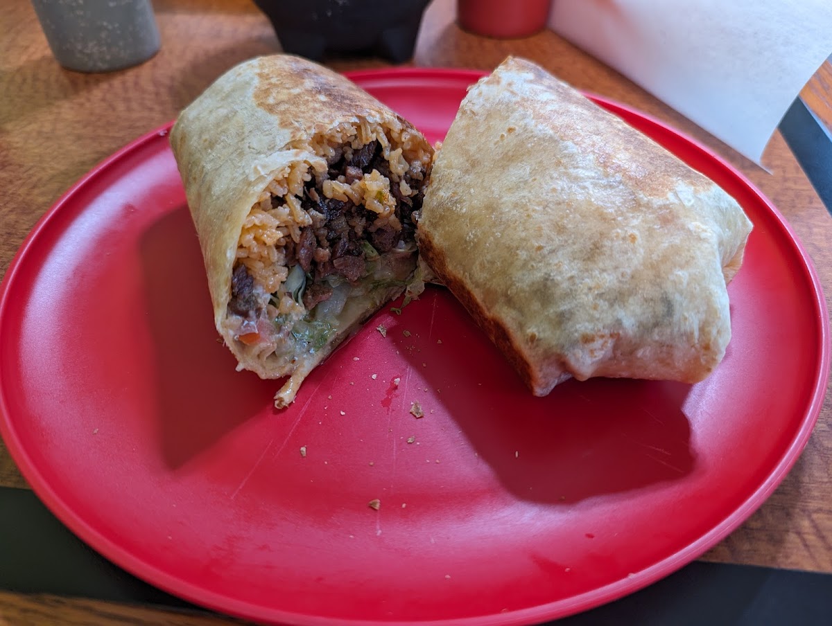 A carne asada burrito cut open on a red plate