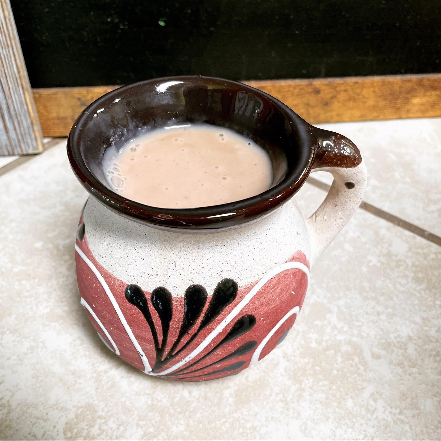 Champurrado served in a traditional red and black Mexican pottery mug